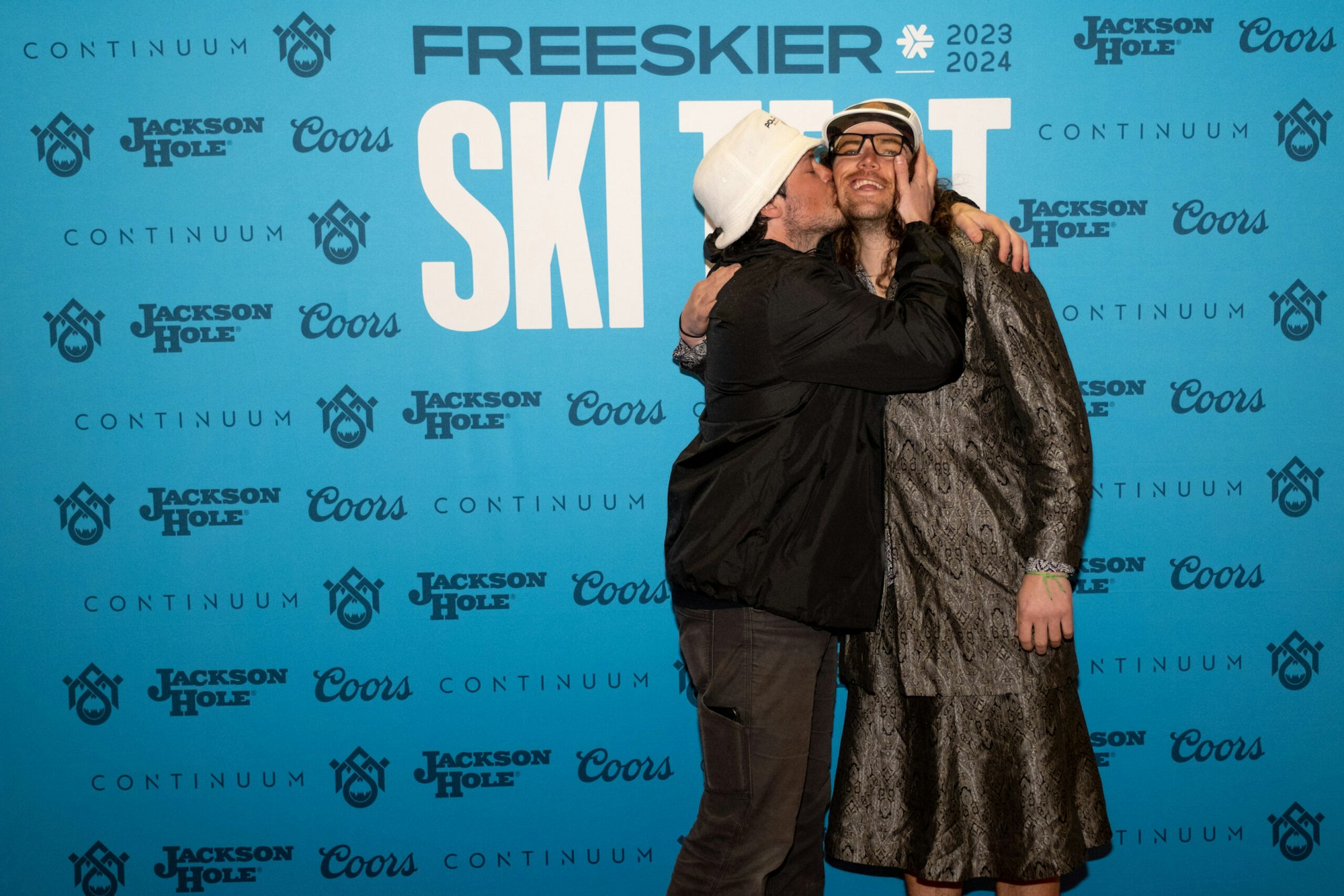2 people pose in front of FREESKIER banner