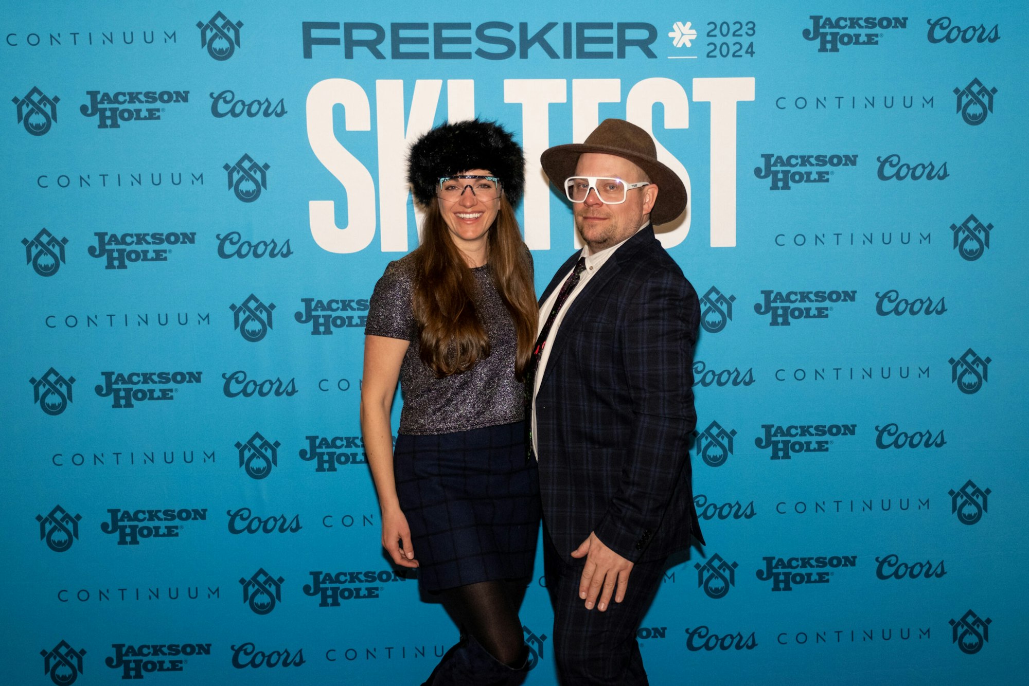 Two people pose in front of FREESKIER banner