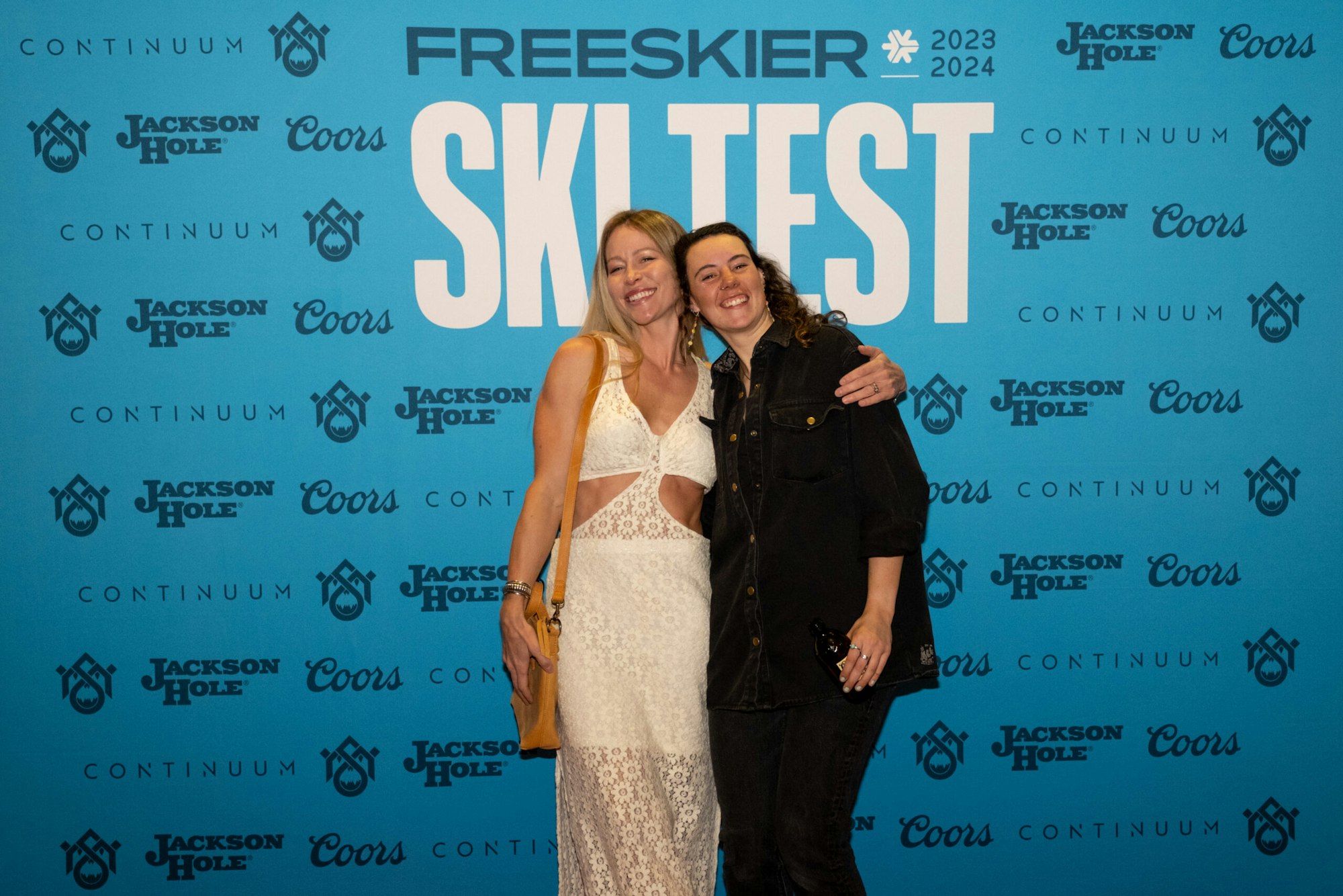 2 people pose in front of FREESKIER banner