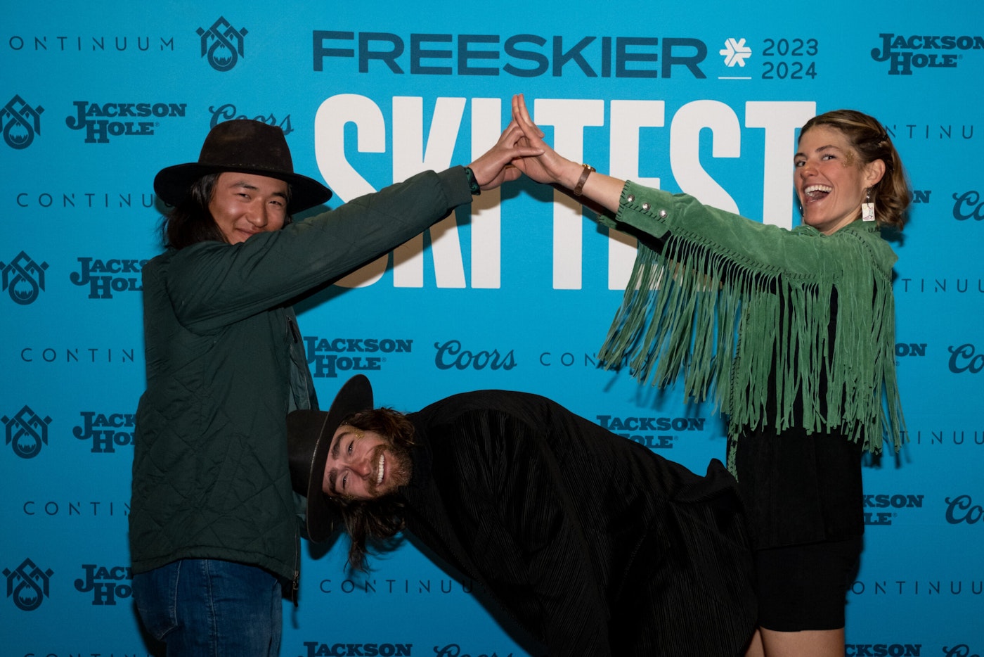 Three people pose in front of FREESKIER banner