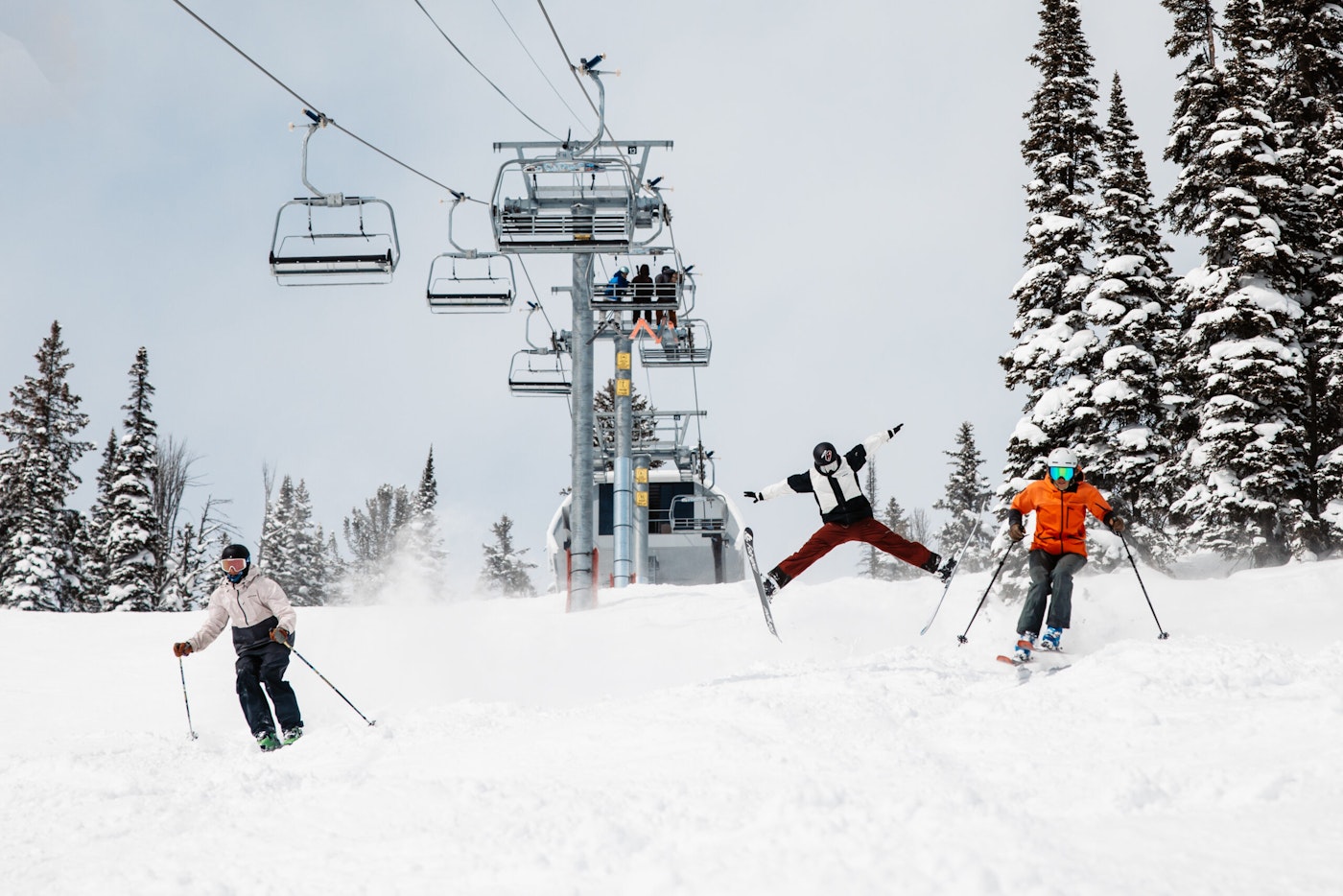 Skiers ski under a chairlift