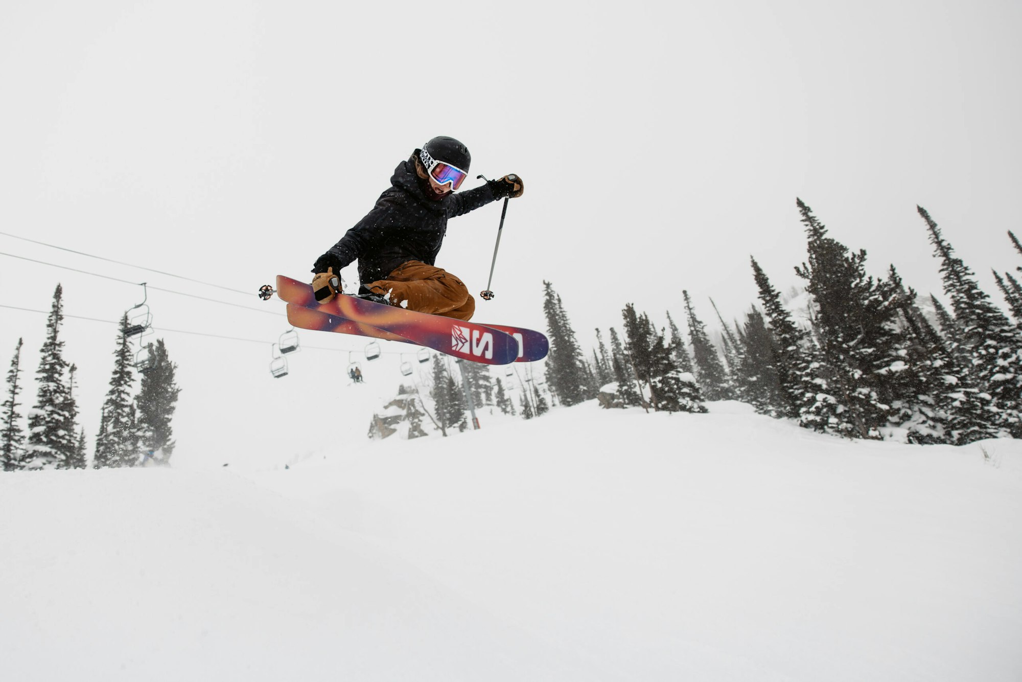 Skier catches air and grabs the side of their skis in deep snow