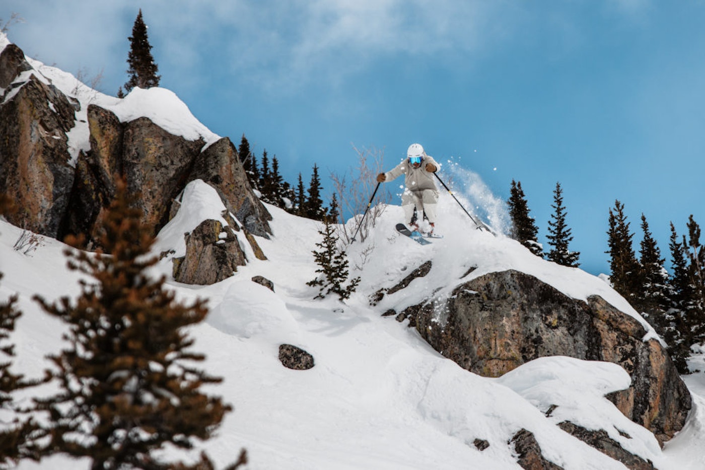 Skier Skis off snow covered rock cliff