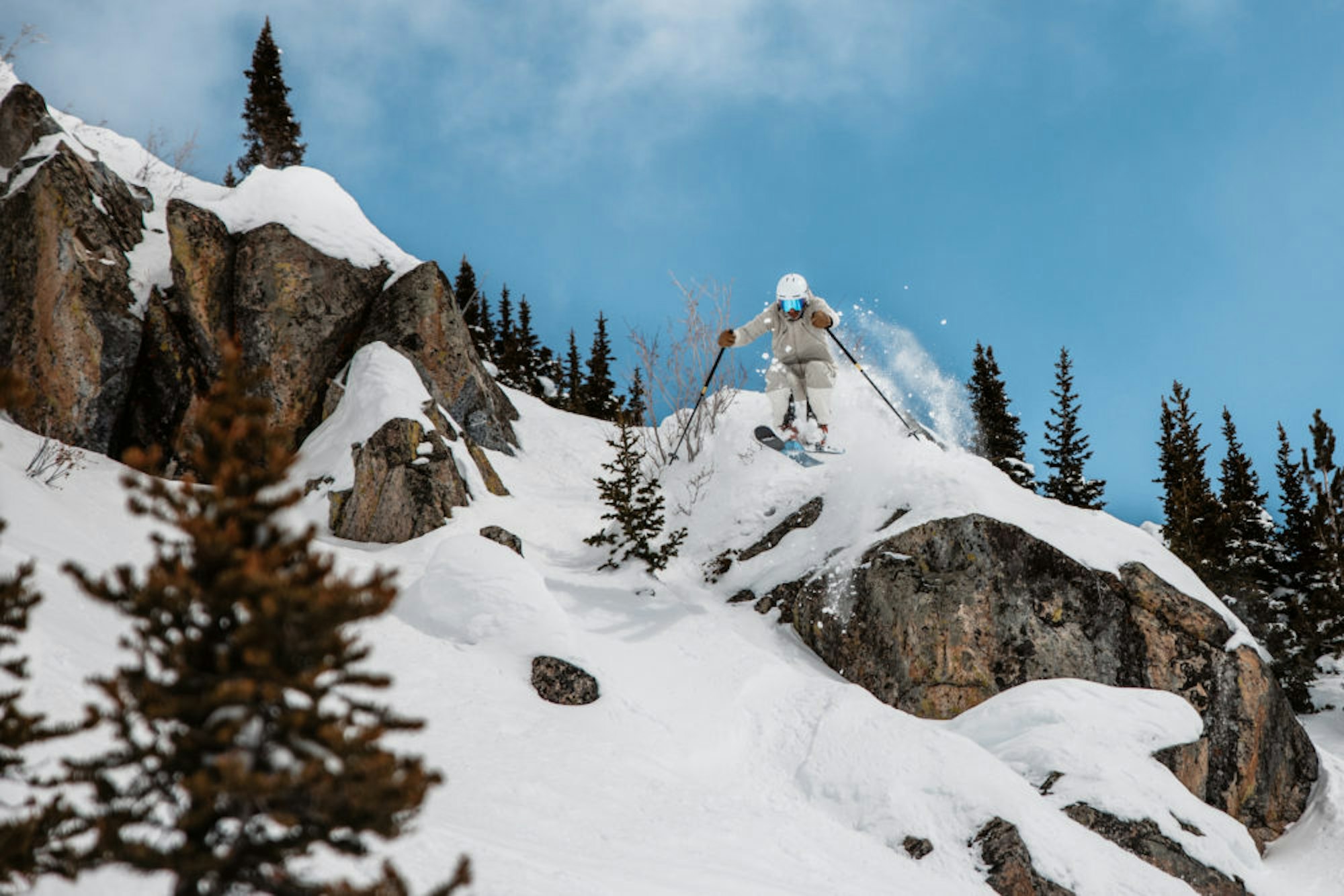 Skier Skis off snow covered rock cliff