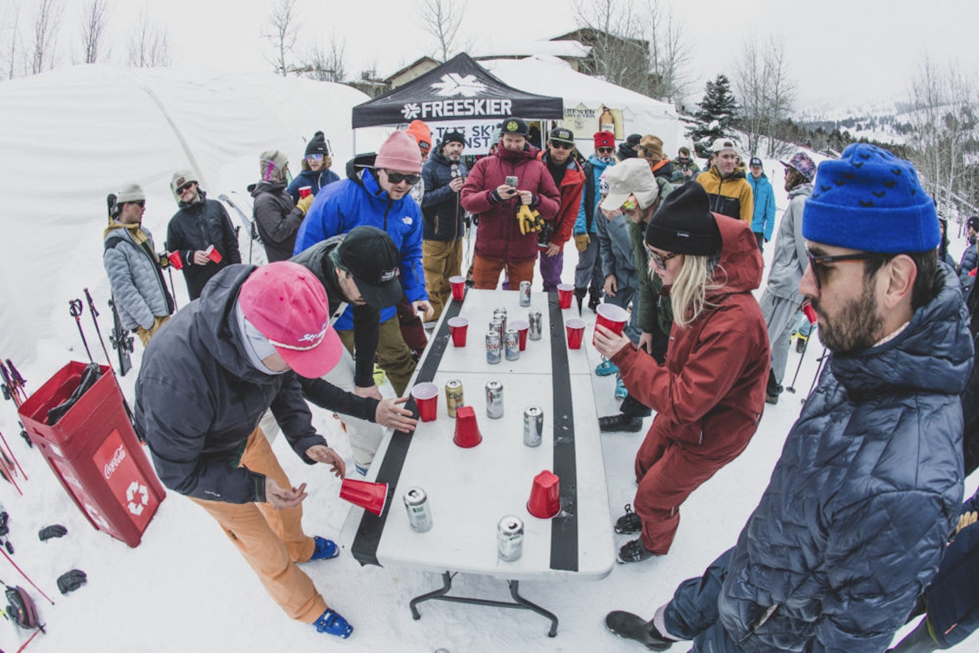 Skiers play flip cup outside with Coors beer