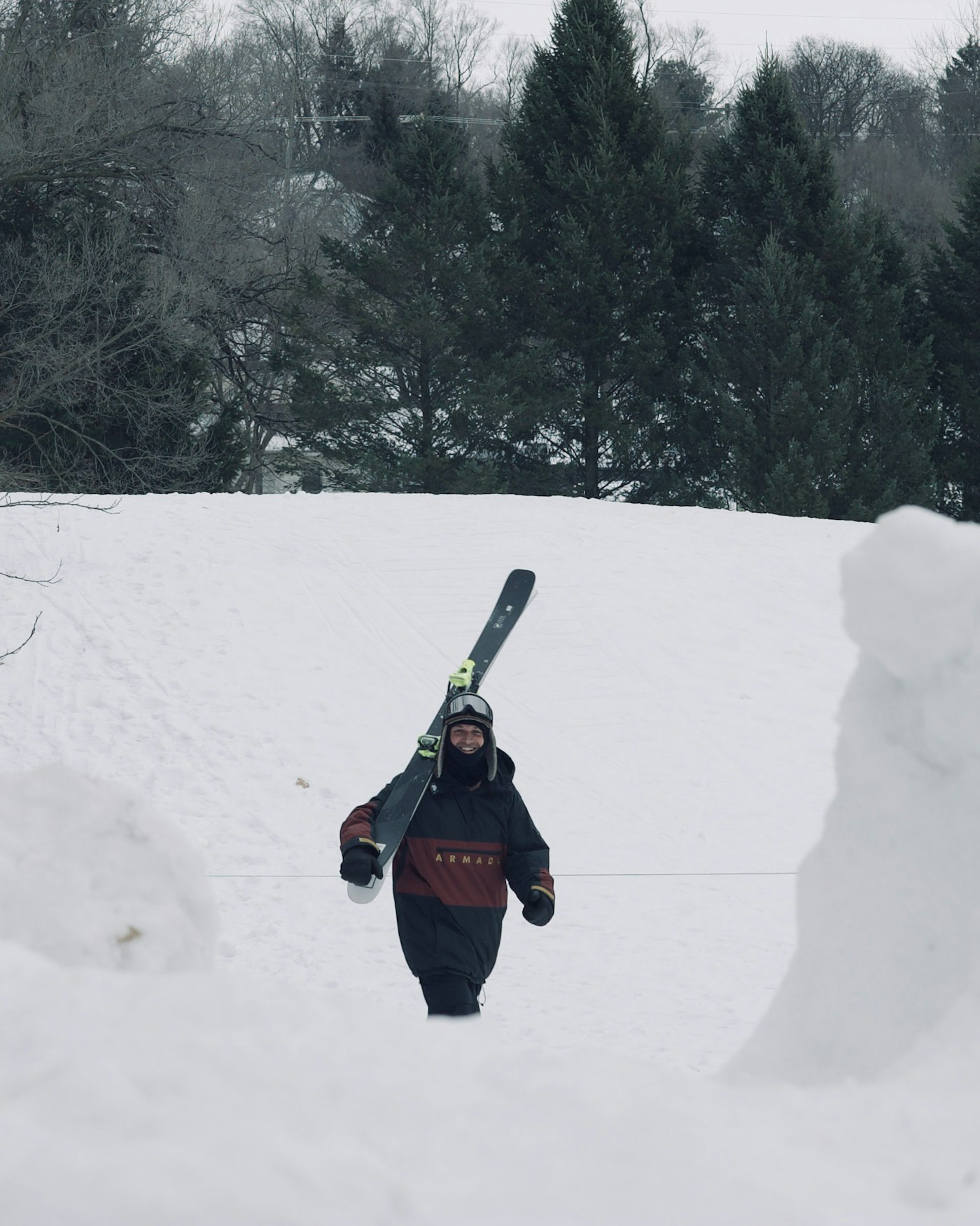 Skier carries skis up a hill toward camera