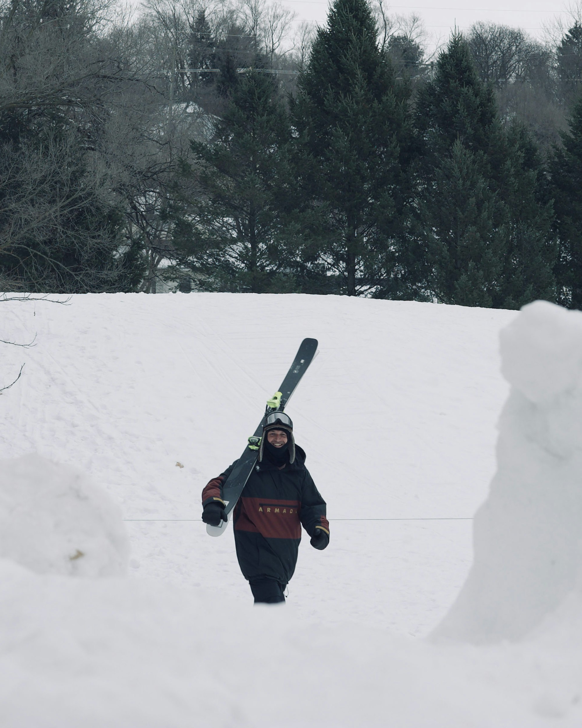 Skier carries skis up a hill toward camera