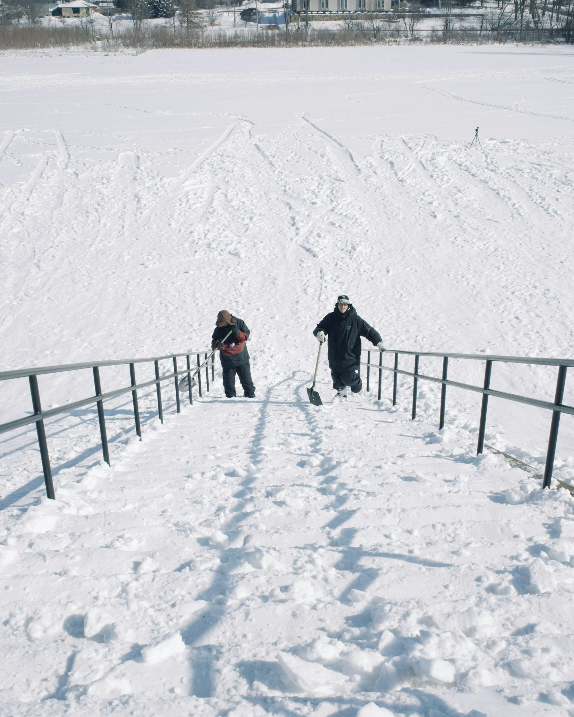 Skiers standing at the bottom of stairs with shovels