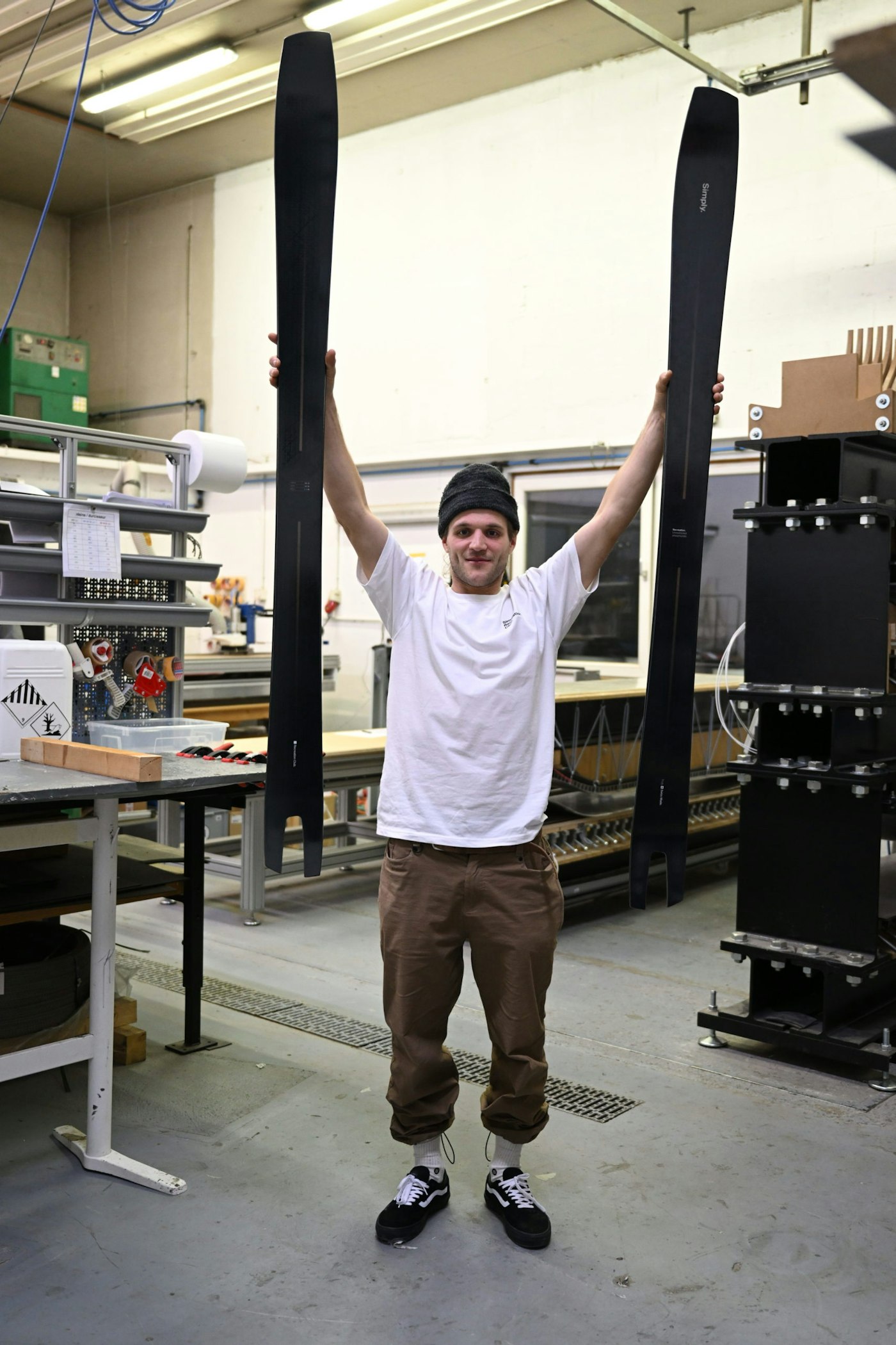 Guy holds 2 swallow tailed skis above his head