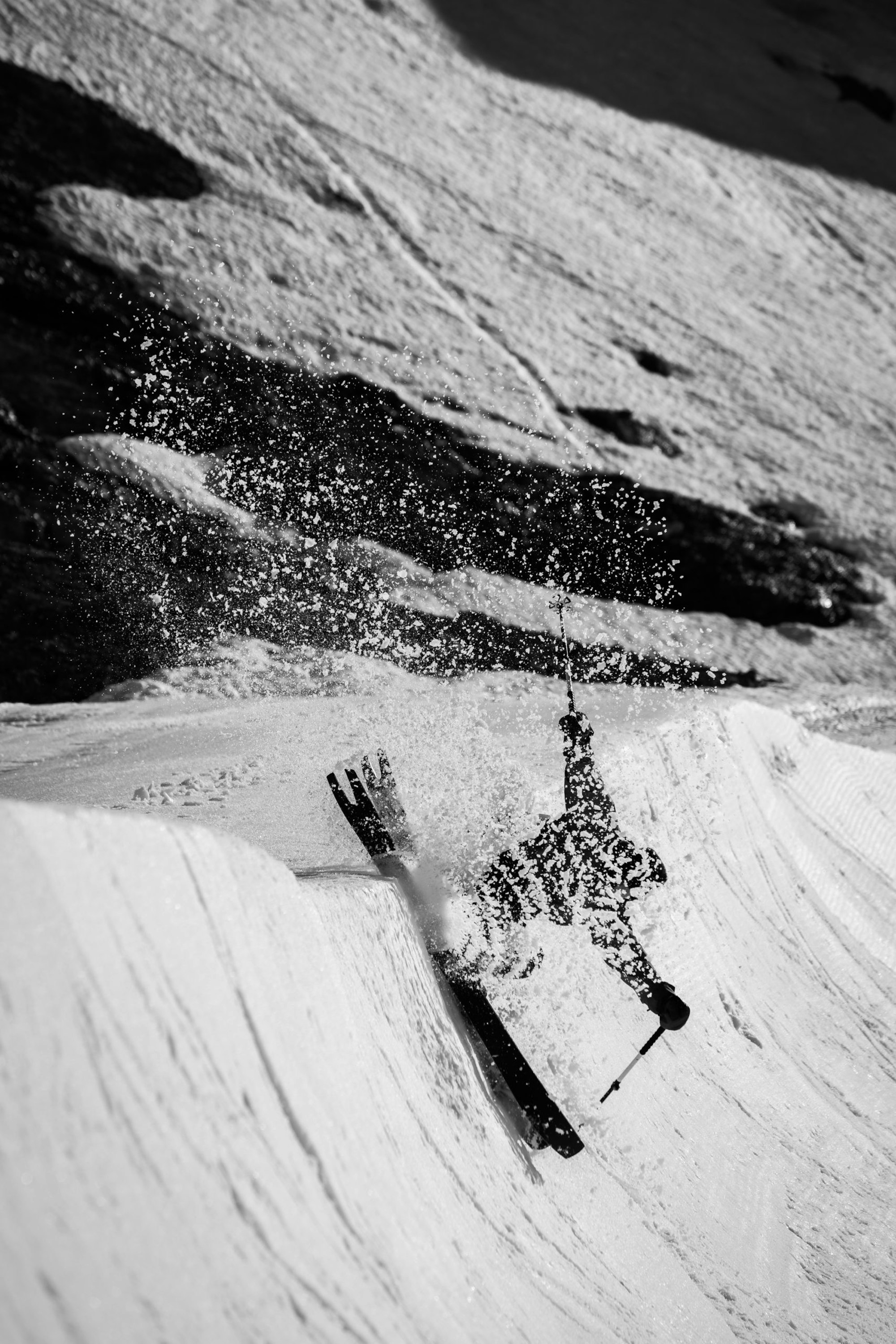 Skier slides the edge of a bowl kicking up snow