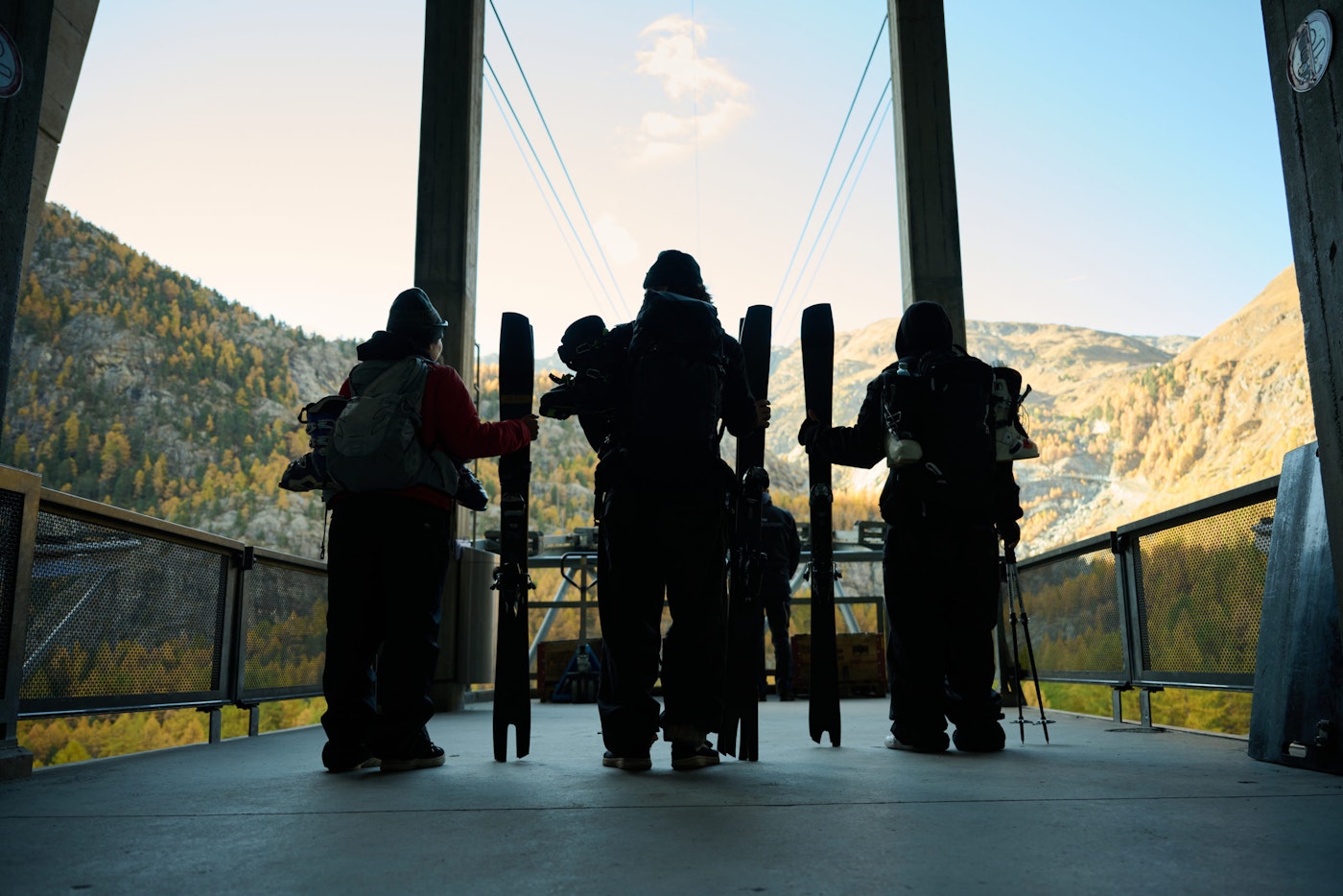 3 Skiers stand at the edge of a tram base