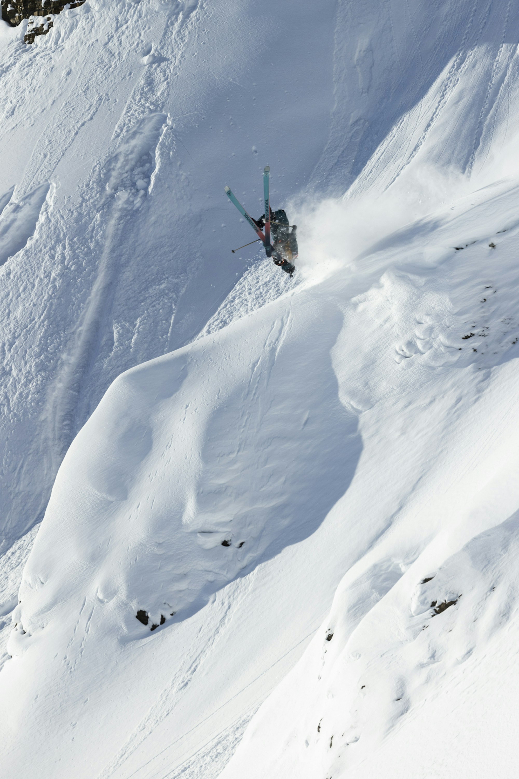 Skier on the Freeride World Tour doing a backflip off a snowy rock