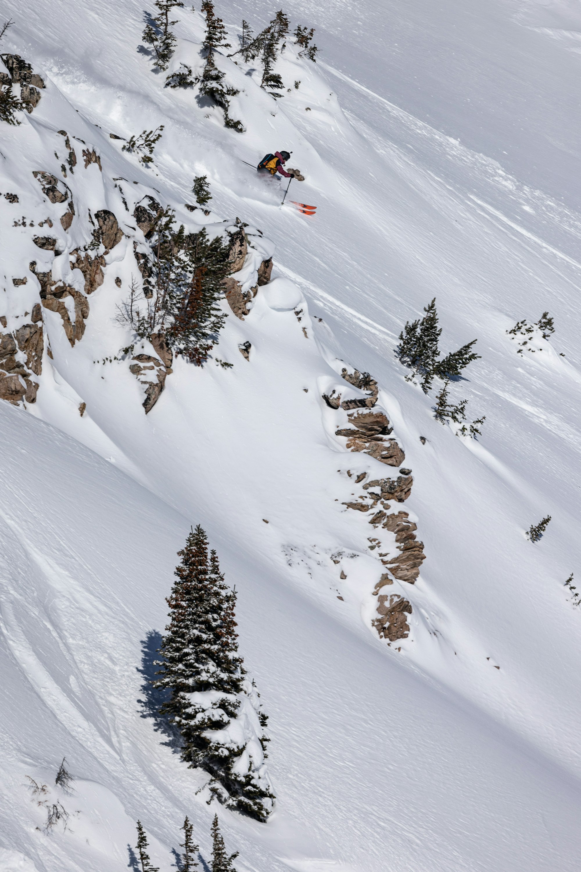 Skier turns through powder snow on a rocky steep wall