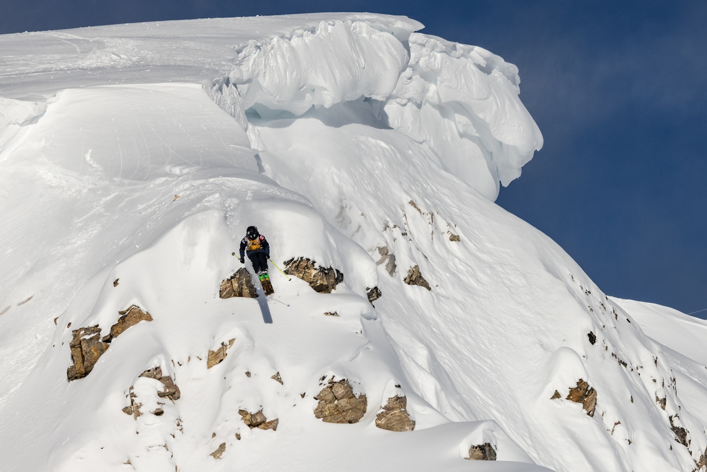 Skier jumps off a small rock covered in snow