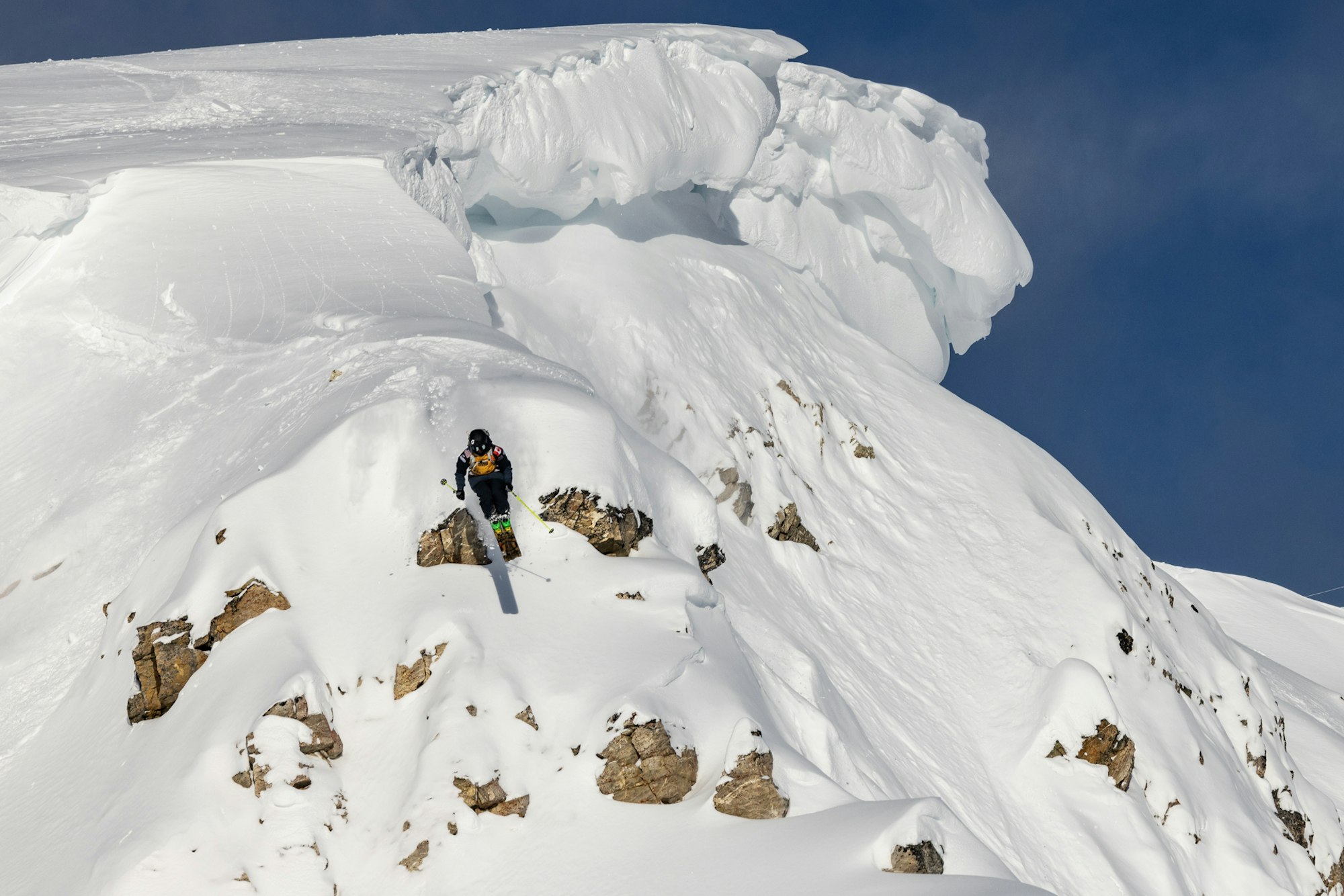 Skier jumps off a small rock covered in snow
