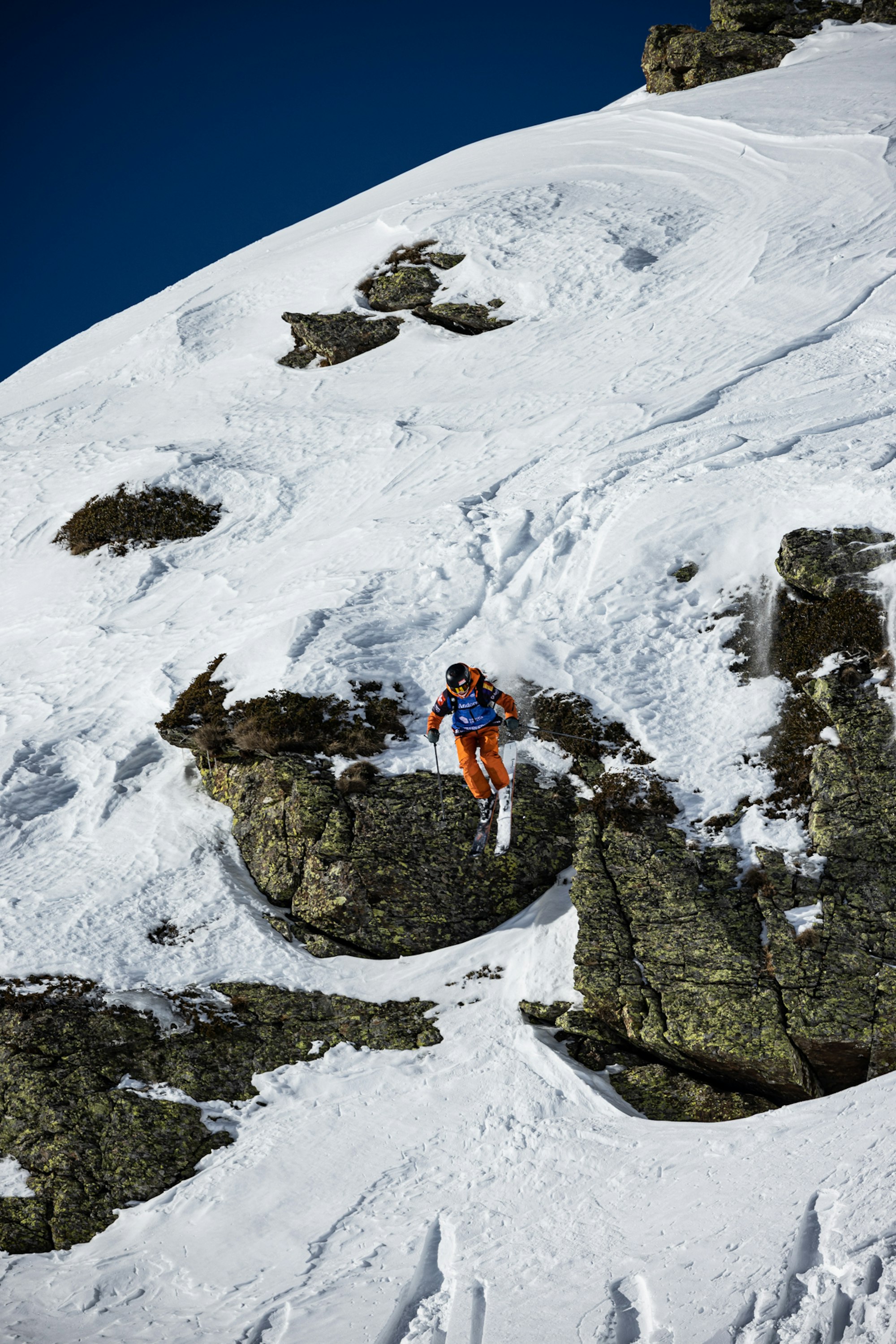 Freeride world tour skier jumping from a snowy rock