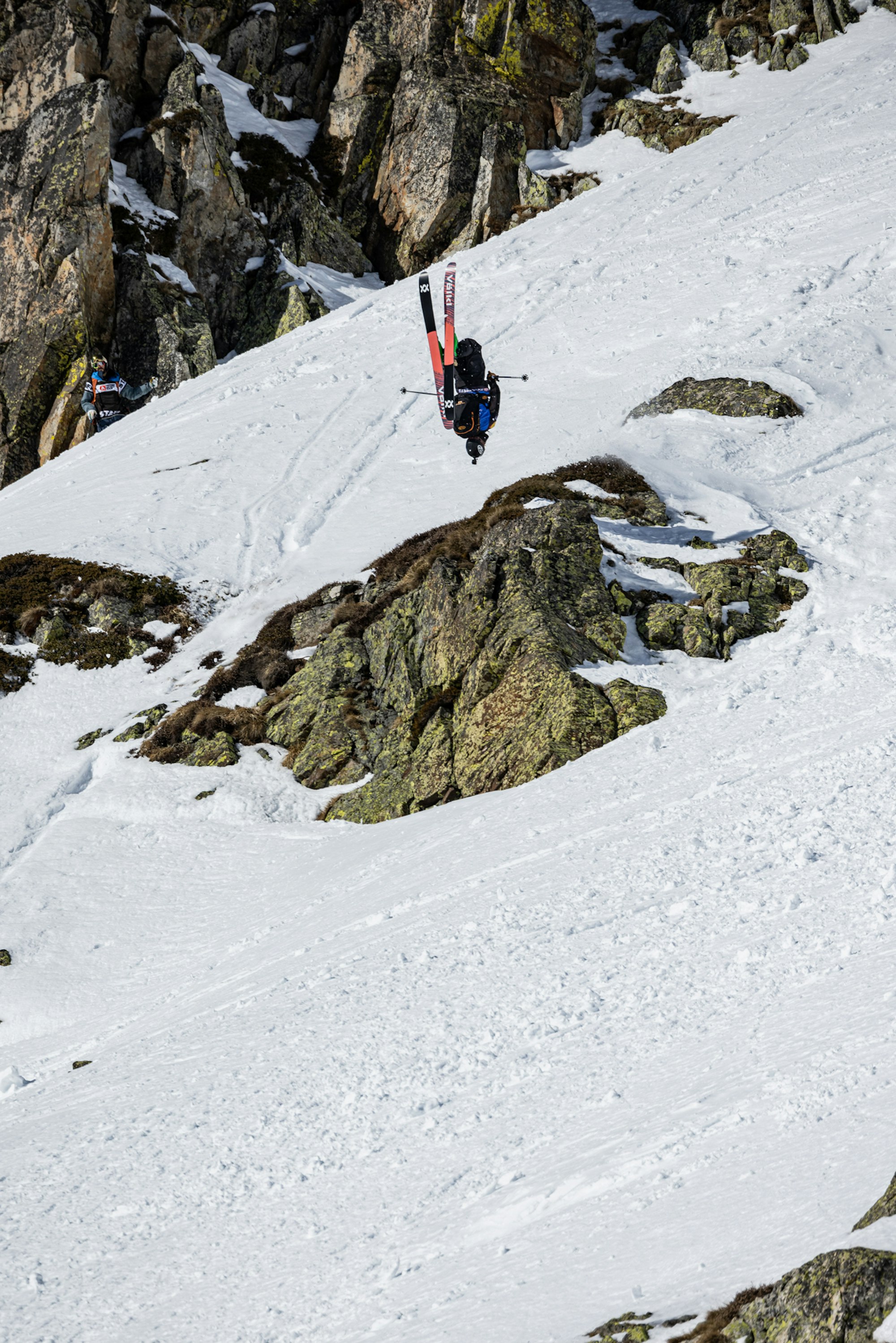 Freeride world tour skier backflips off a snowy rock