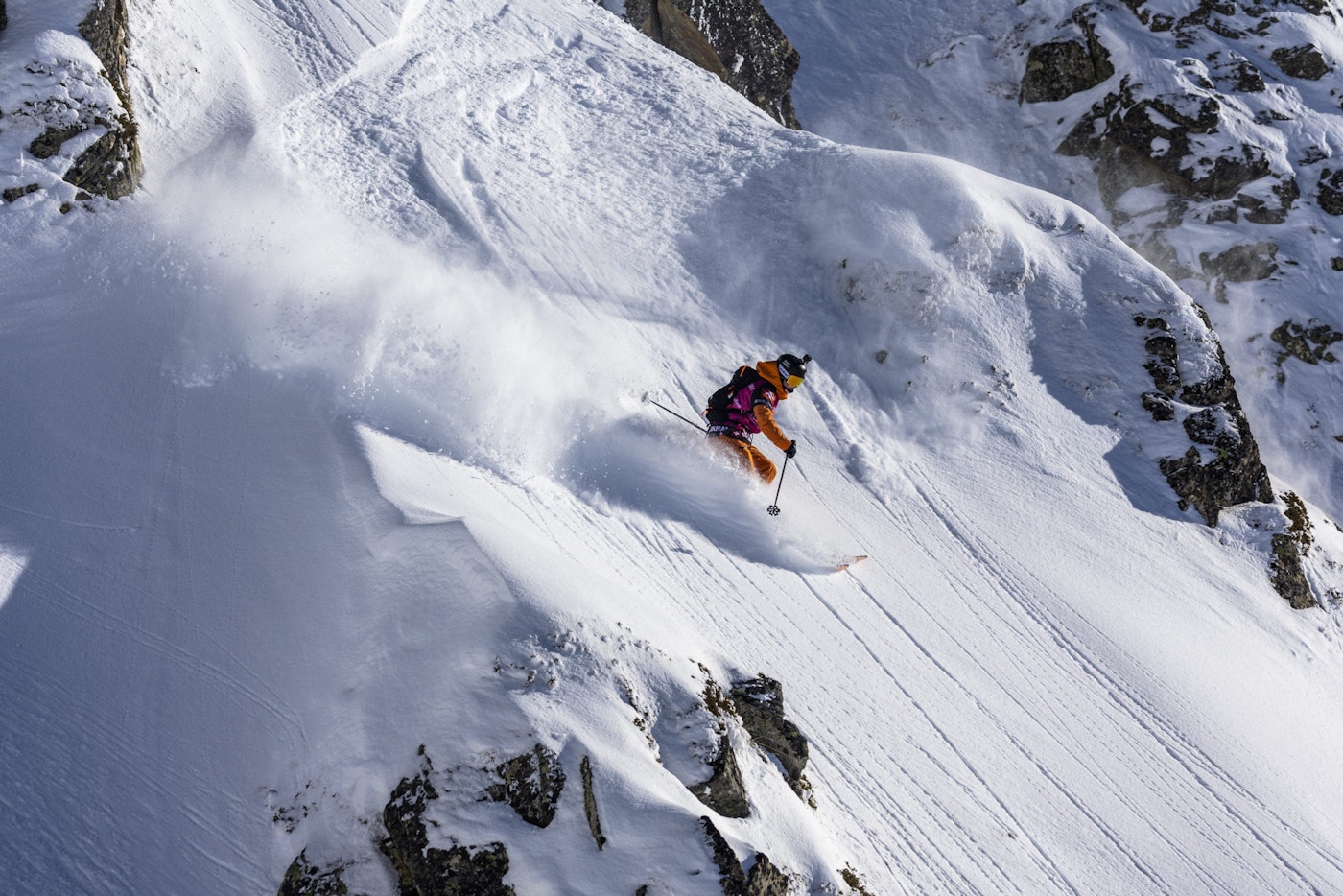 Freeride world tour skier skis in deep snow on a rocky face