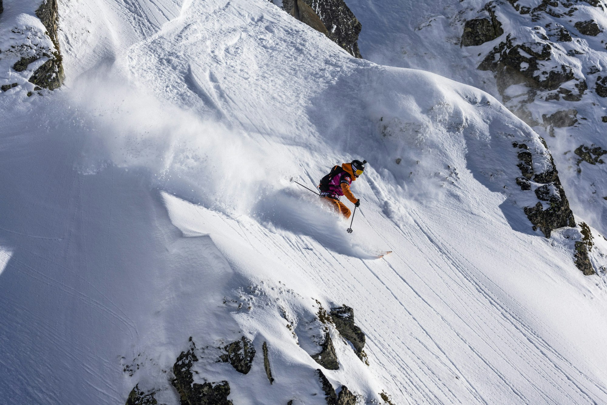 Freeride world tour skier skis in deep snow on a rocky face