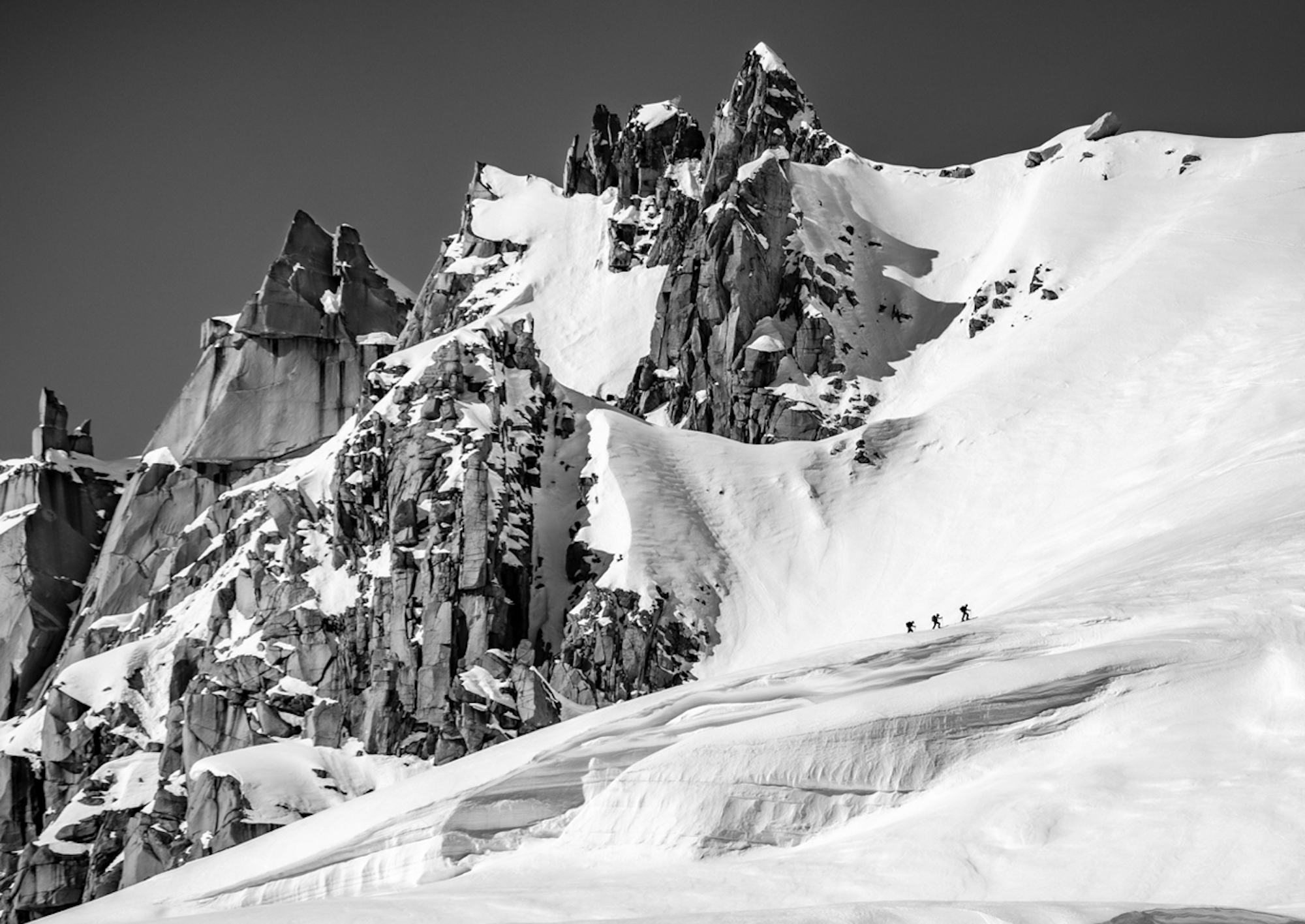 3 skiers skin up to the top of a mountain on Alaska