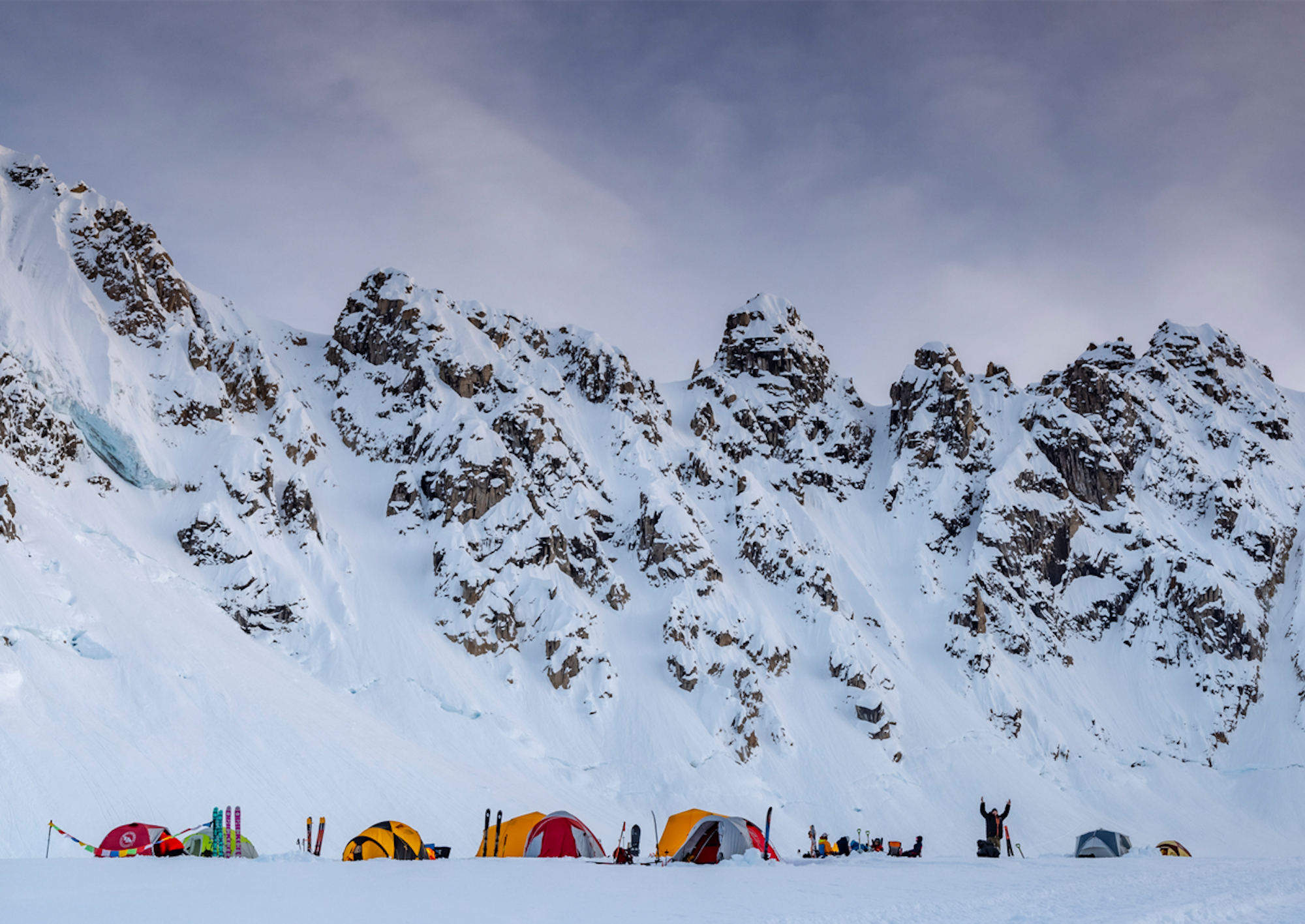 Skiers camping at the base of high peaks