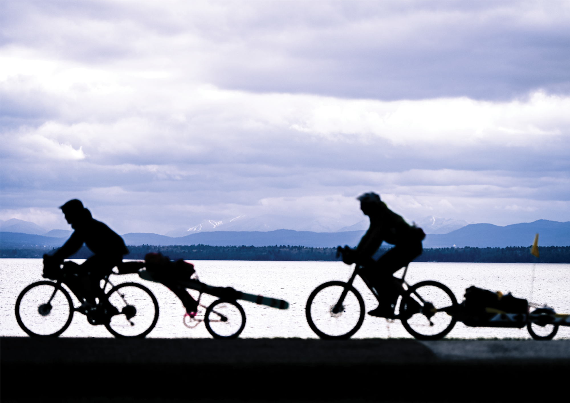 Alex Goff and Nate Trachte bike their skis along a lake in the Adirondacks