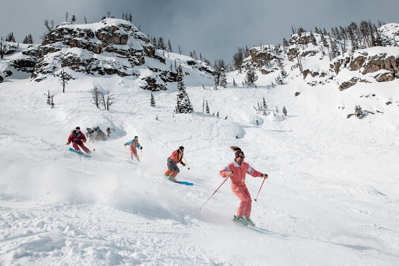 5 skiers skiing in a line down a snowy slope