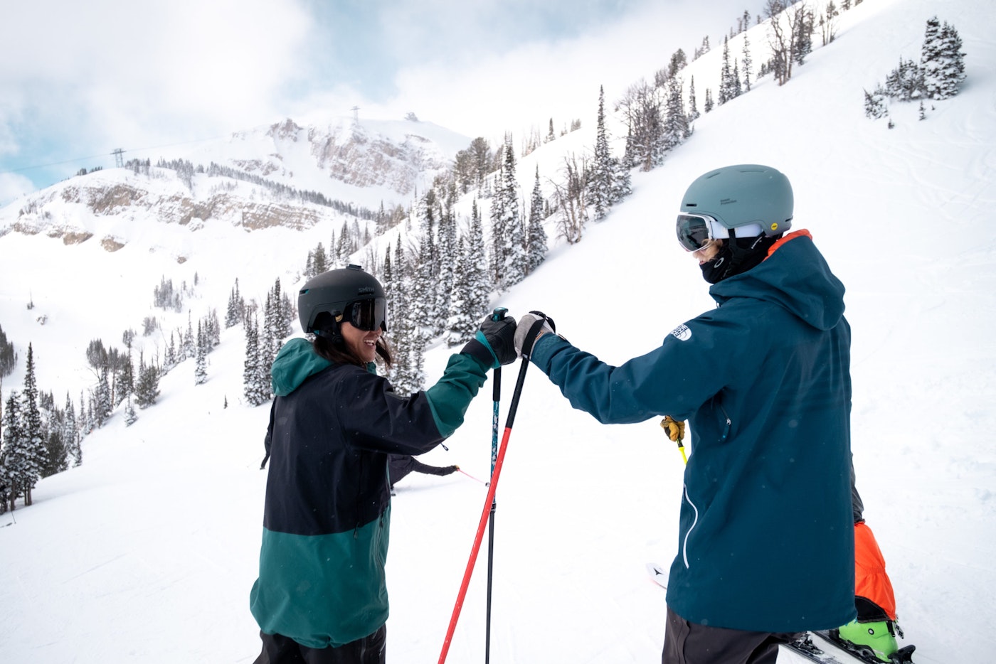 Two skiers fist bump on a hill