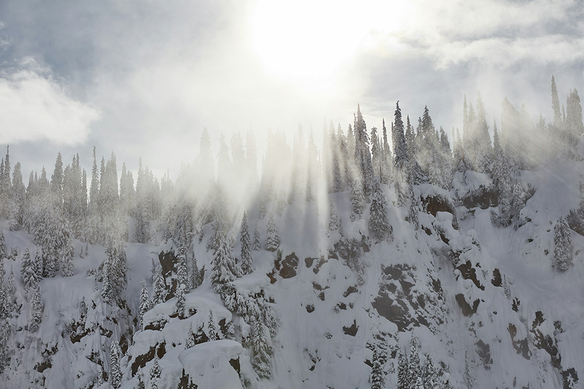 Beams of light press through the clouds at Eagle Pass Heliskiing