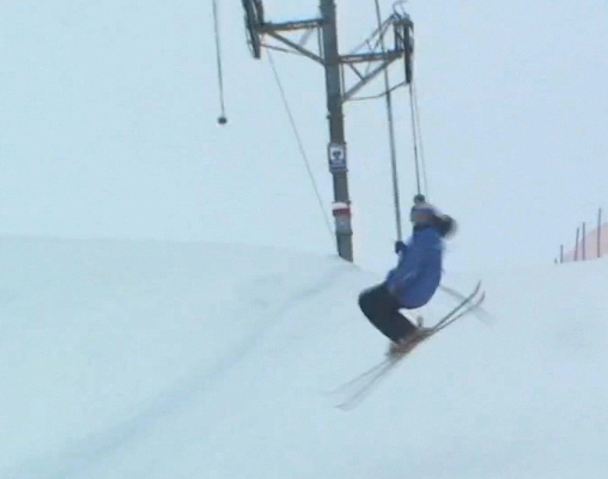 Skier stomps uphill double flatspin while riding Poma lift