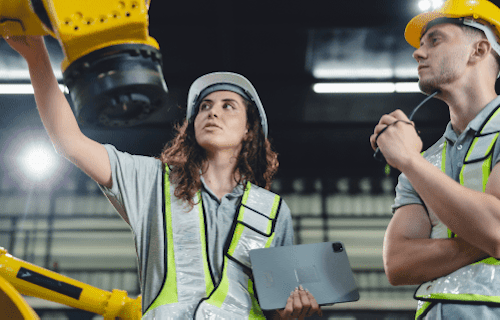 Workers in yellow hard hats inside a warehouse