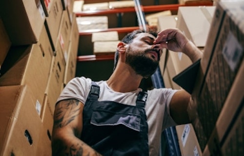 A stressed worker sitting with eyes closed.