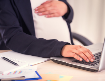 A pregnant employee working on a laptop