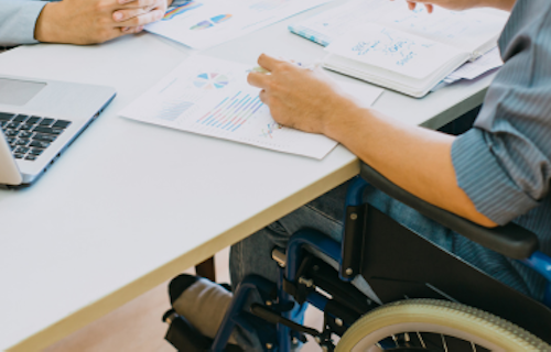 An injured worker in a wheelchair filling out paperwork.