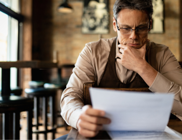 A small business owner sitting in his cafe and reading about the new changes under Bill 30