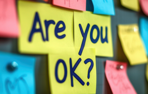 A softboard with colourful post-its that say: Are you ok?
