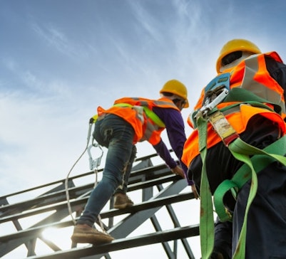Construction workers working at heights with safety harnesses on