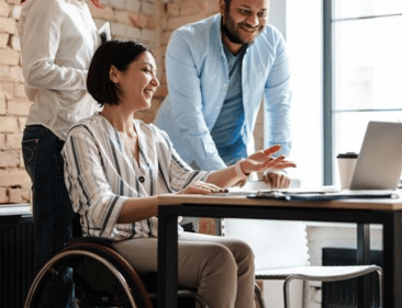Employee in a wheelchair talks to colleagues during a work meeting.