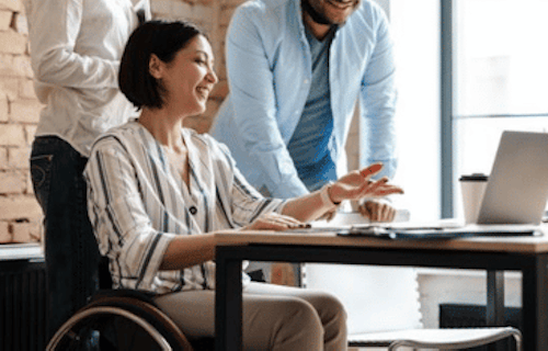 Employee in a wheelchair talks to colleagues during a work meeting.