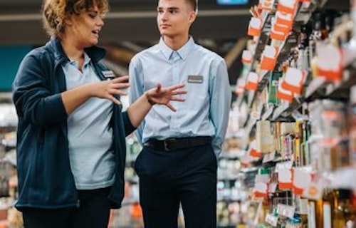 A student worker being by a grocery store employee