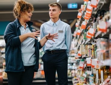 A student worker being by a grocery store employee