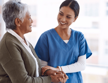 An Imani caregiver helping an elderly woman walk around.
