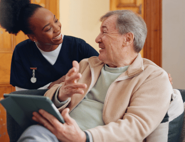 An Imani caregiver helping an elderly man move around
