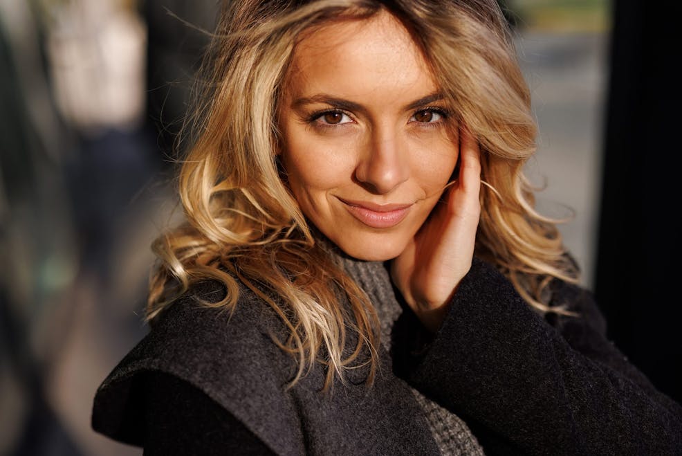 blonde woman grinning with her hand on her cheek