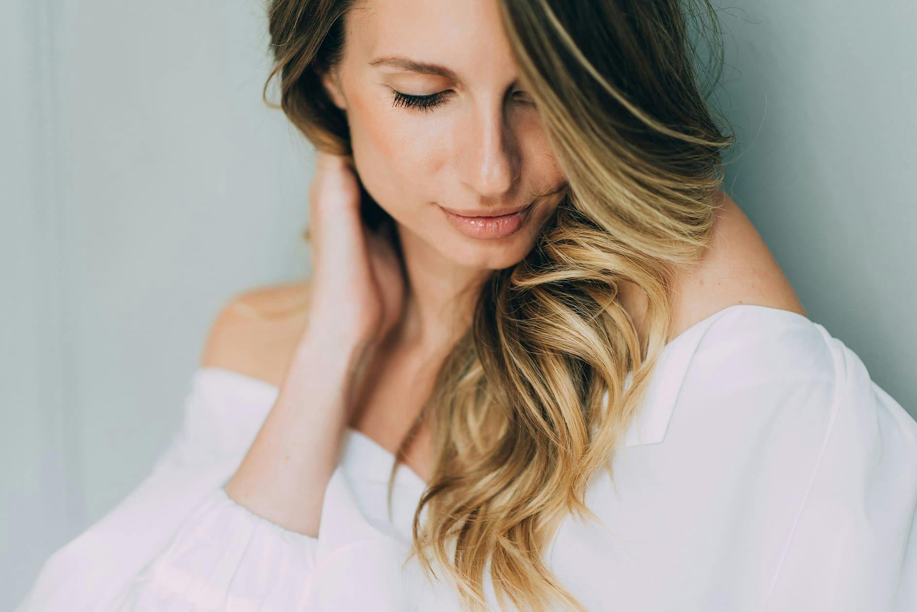 woman looking down while touching her hair