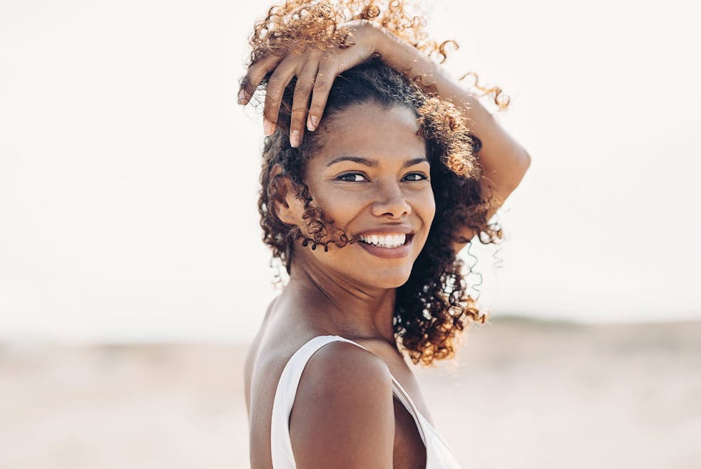 woman moving her hair out of her face as the wind is in her face