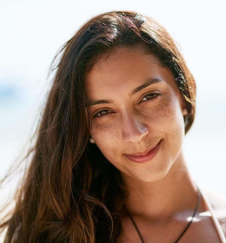 brunette woman with freckles smiling and looking forward