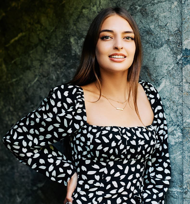 woman leaning against a wall in black and white dress