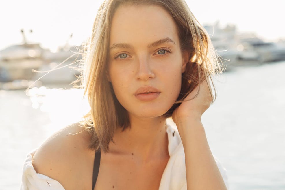 woman looking forward while moving her hair behind her ear