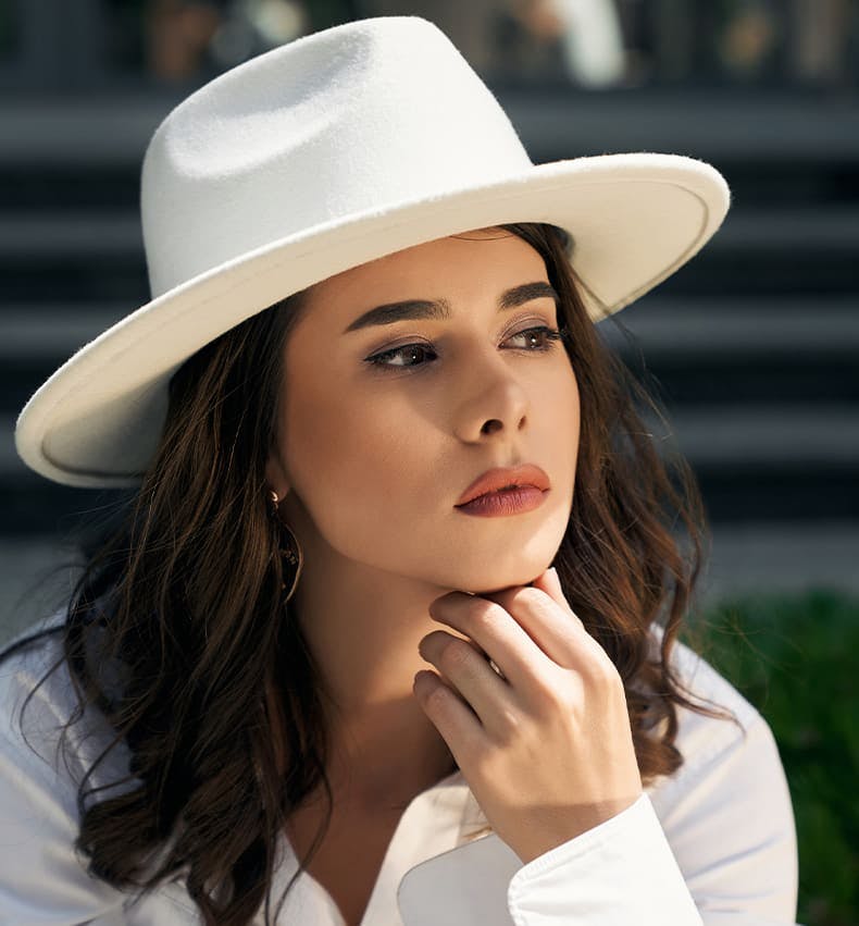woman resting hand under her chin with white hat